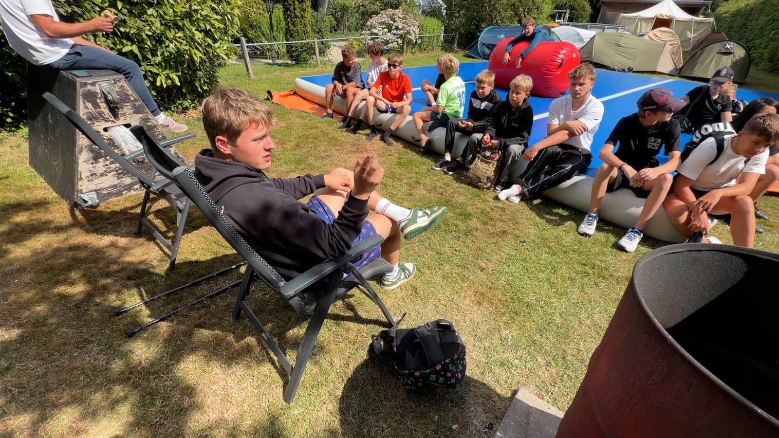 De kampgroep luistert buiten naar een begeleider