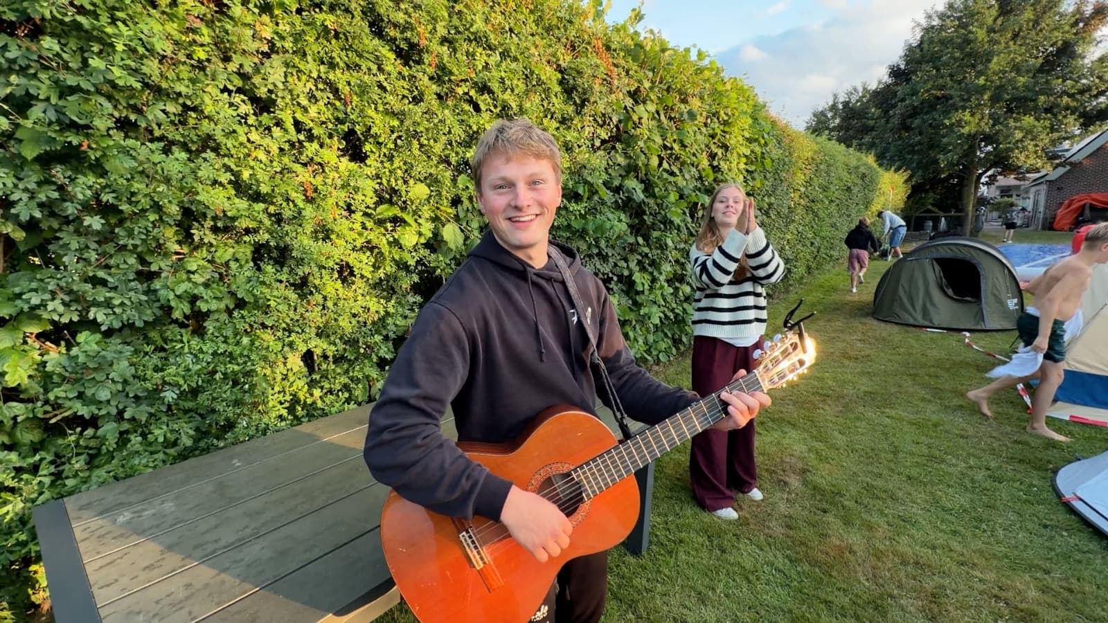 Een begeleider speelt gitaar tussen de tenten