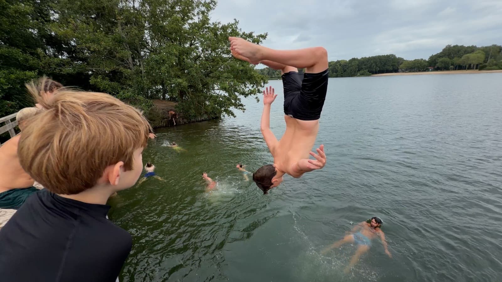 Een deelnemer maakt een salto vanaf de steiger boven het water