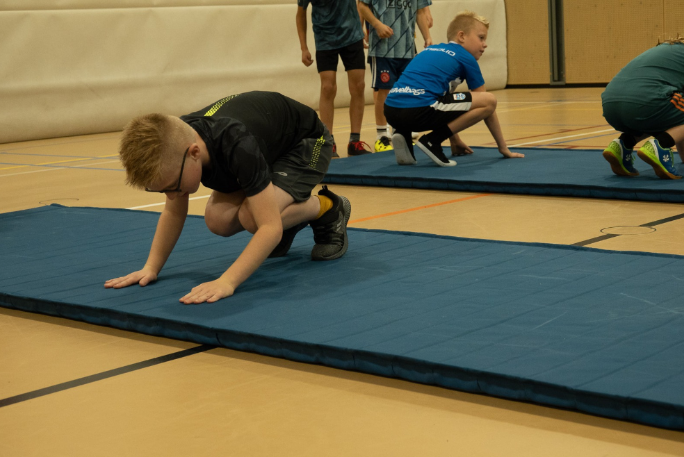Kinderen oefenen grondvormen — lopen, springen, landen, rollen, klimmen